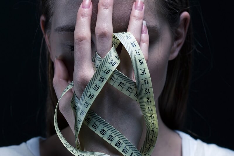 kobieta z bulimią zasłania twarz miarką