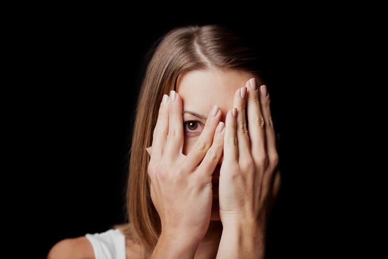 Kobieta patrząca przez palce: lęk albo fobia