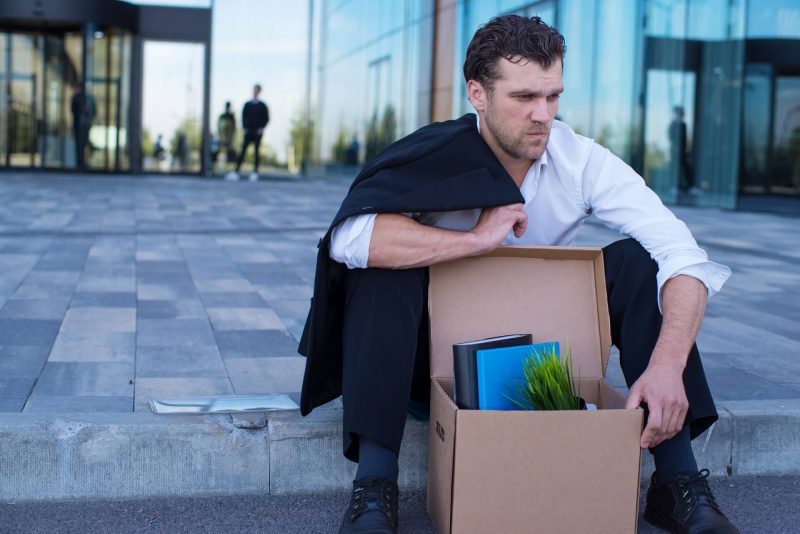 Mężczyzna, który stracił pracę siedzi na chodniku przed biurem