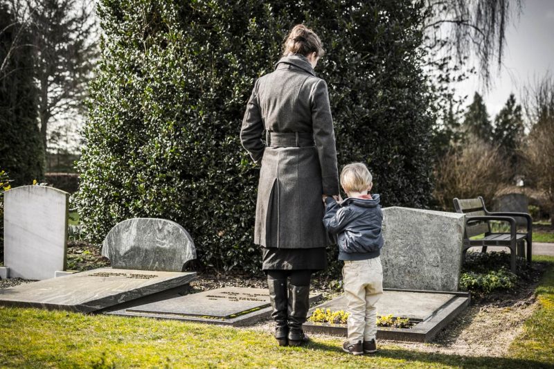 Kobieta i dziecko w żałobie stoją przy grobie